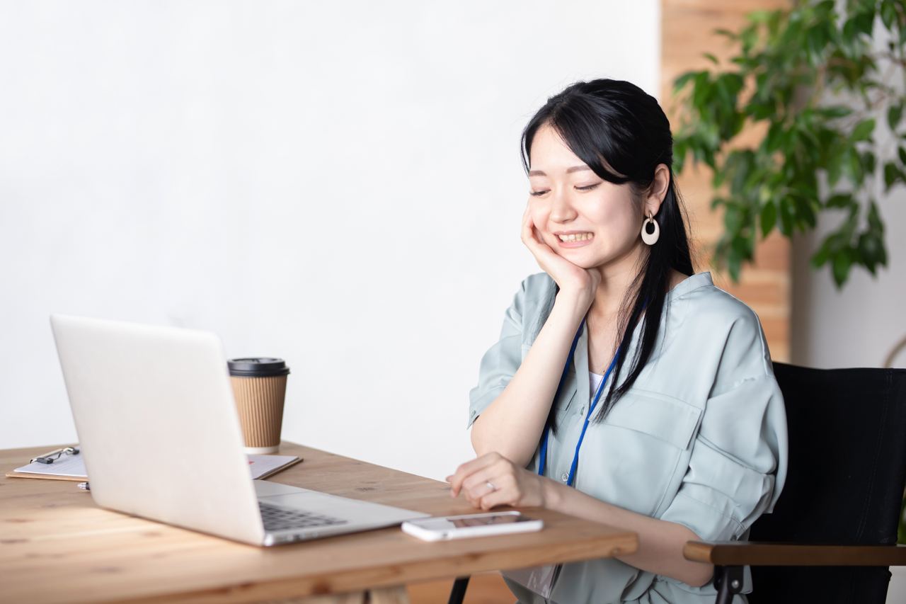 A woman smiling while working on her laptop, possibly relieved after TMD/TMJ treatment in Surrey, BC
