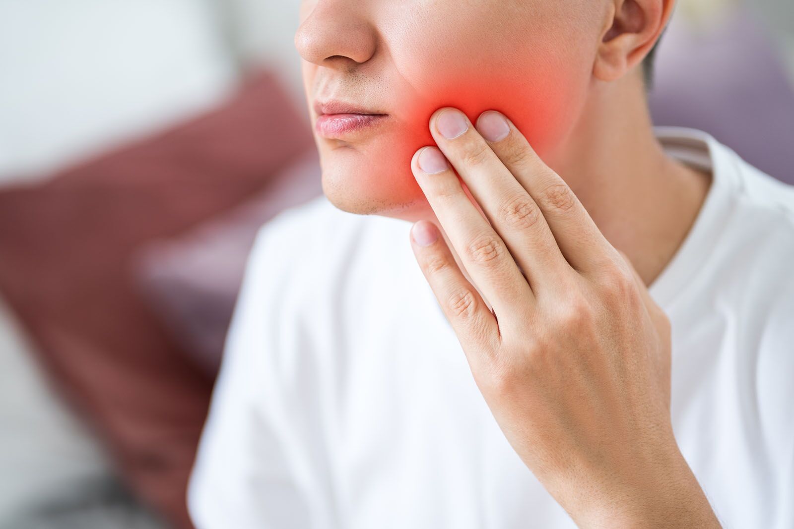 A person holding their cheek in pain, needing an emergency dentist in Surrey, BC.